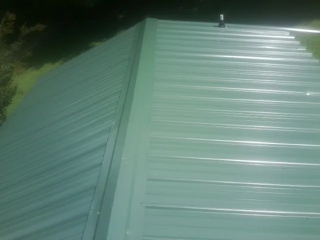 New green metal panels meeting at the ridge of a roof — Flat Roof Repair work by our crew in Triangle
