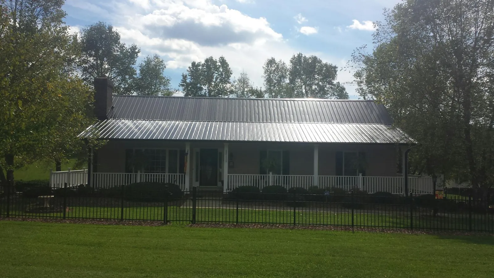 Gray metal roof on a brick ranch with a full width front porch — Gutter Guard Installation work by our crew in Triangle