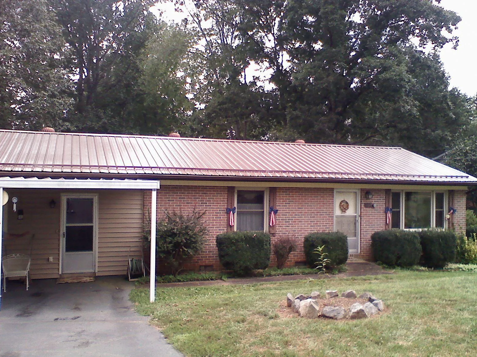 Bronze metal roof and carport on a brick ranch home — Roof Repair work by our crew in Triangle
